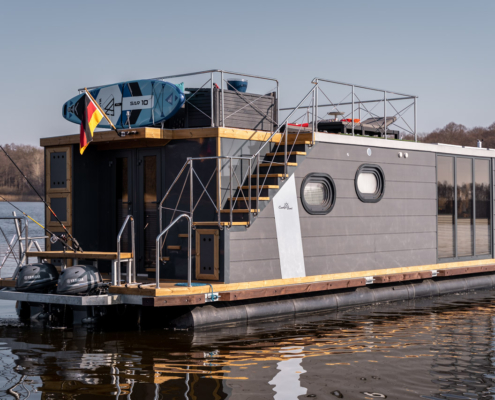 Über eine breite Holztreppe erreichen Sie ganz bequem die große möblierte Dachterrasse, die zum Sonnenbaden oder einen gemütlichen Grillabend einlädt.